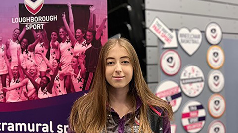 Student standing in front of sport signs